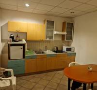 Kitchen corner with wooden cabinets, microwave, refrigerator, and table in warehouses and halls.