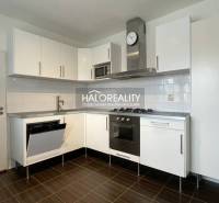 A kitchen with built-in appliances, white cabinets, and a dark floor in a 3-room apartment.
