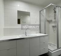 A bathroom in a 3-room apartment with white tiles, a shower corner, and a sink with a cabinet.