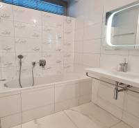 A bathroom with a bathtub, sink, and light tiles in a 3-room apartment.