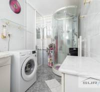Bathroom in a 3-room apartment with a washing machine, shower corner, and wall decoration.