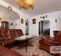 Living room in a three-room apartment with a sofa, armchairs, and a decorative mirror on the wall.