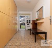 A hallway with storage spaces and a bench, view of blooming trees.