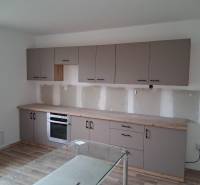 A kitchen in a family house with a wooden decor floor and gray cabinets.