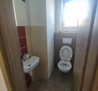 Bathroom in a family house with a sink and toilet, tiled floor.