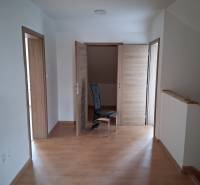 A room in a family house with a wooden decor floor and three wooden doors.