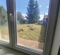 A view from a family house in Ľubela into a garden with a well-maintained lawn and trees.