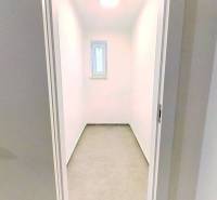 A narrow room with a small window and white walls in a 2-room apartment.
