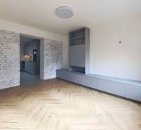 Living room in a two-room apartment with a wooden decor floor and brick cladding.