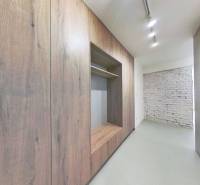 A hallway in a 2-room apartment with wooden decor and a brick wall.