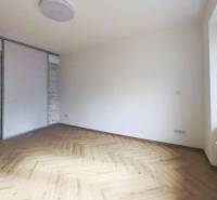 A room in a 2-room apartment with a wooden decor floor and a large window.