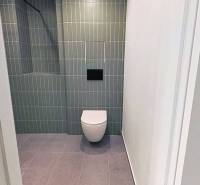 Bathroom in a 2-room apartment with a modern toilet and tiles.