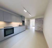 A kitchen in a 2-room apartment with modern lighting and tiles on the wall.