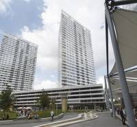 High-rise buildings in the area on Landererova Street, people relaxing by the fountain and trees.