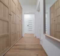 A hallway in a family house with plenty of storage space and a wooden-patterned floor.