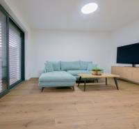 A living room in a family house with a wooden decor floor, light furniture, and a television.