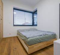 A bedroom in a family house with a bed, wardrobes, and a floor with a wooden decor.