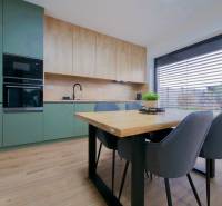 A kitchen in a family house with a wood-patterned floor, green cabinets, and a dining table.
