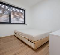 A bedroom with a bed and a wooden decor floor in a family house.
