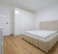 Bedroom in a family house with a bed and a wardrobe, floor with wooden decor.