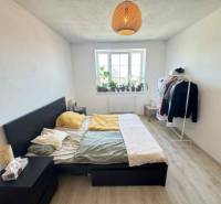 Bedroom in a 2-room apartment with a bed, nightstand, and clothes rack.