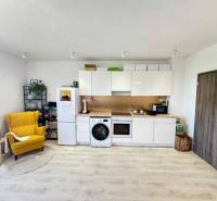 A kitchen in a 2-room apartment with white cabinets and a yellow chair, a floor with a wooden decor.