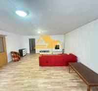 Living room in a two-room apartment with a wooden decor floor and a red sofa.