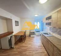 A kitchen in a 2-room apartment with wooden floor decor and light furniture.