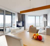 Living room in a three-room apartment with a wooden decor floor and a view from the balcony.