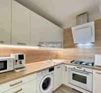 A kitchen in a 2-room apartment with modern appliances and a wooden decor floor.