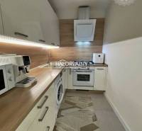 A kitchen in a 2-room apartment with a wooden decor floor and appliances.