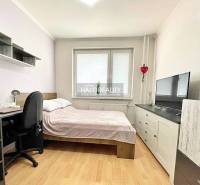 Bedroom in a two-room apartment with a bed, desk, and television. Floor with wooden decor.