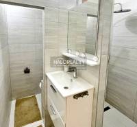 A bathroom with a white sink and a large mirror in a 2-room apartment.