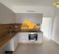 A kitchen in a 3-room apartment with a wooden decor countertop and white cabinets.