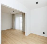A room in a 3-room apartment with a wooden decor floor, curtains, and a French window.