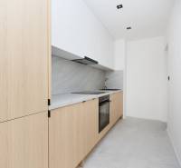 A minimalist kitchen in a 3-room apartment with wooden decor and white cabinets.