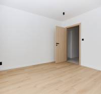 A room with a wooden decor floor and a door in a 3-room apartment.