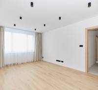 A spacious room with a wooden decor floor and a large window in a 3-room apartment.