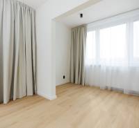 A room with a wooden decor floor and large windows in a 3-room apartment.