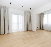 A room in a 3-room apartment with a wooden decor floor and large windows.