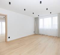A spacious room in a 3-room apartment with a wooden decor floor and curtains.