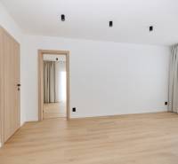A room with white walls, a floor with a wooden decor, and curtains in a 3-room apartment.