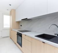 A kitchen in a 3-room apartment with a simple set-up and a black sink.