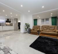 Living room in a family house with a sofa set and kitchen area.