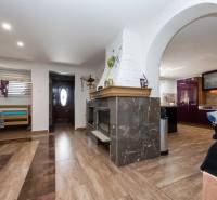 Interior of a family house with a fireplace, wooden floor decor, kitchen, entrance doors.