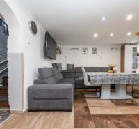 Living room with a corner sofa, table, and wooden decor flooring in a family house.