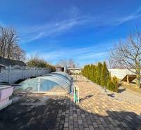 A garden with paving and a covered swimming pool in a family house in Dvorníky.