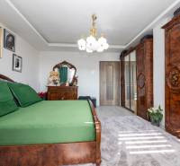 Bedroom with wooden furniture and green bed linens in a family house.