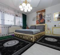 A bedroom in a family house with an upholstered bed and decorative curtains.