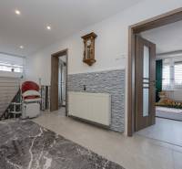 A hallway in a family house with a clock on the wall and a stairlift.